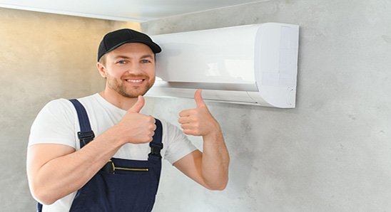 smiling young male electrician repair conditioner in client home. man mechanic or repairman fix filters in air condition device at customer house